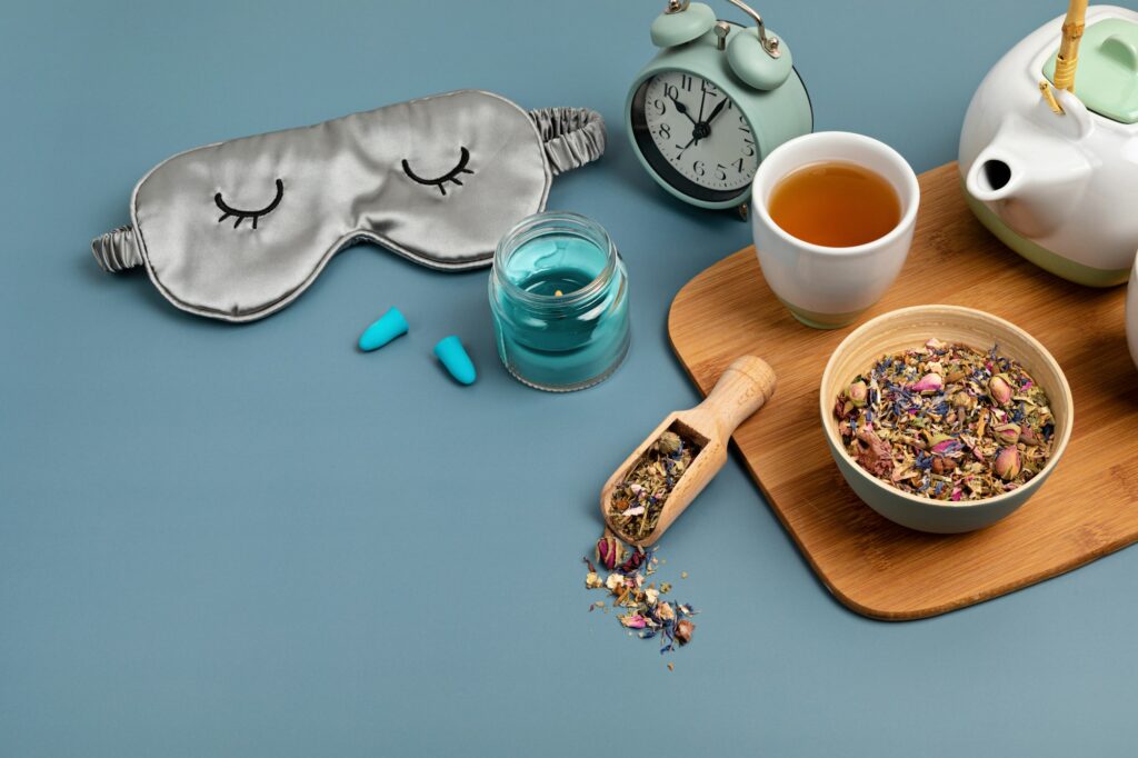 Alarm clock, sleeping mask, tea pot on blue background. Quality of sleep, good night, insomnia